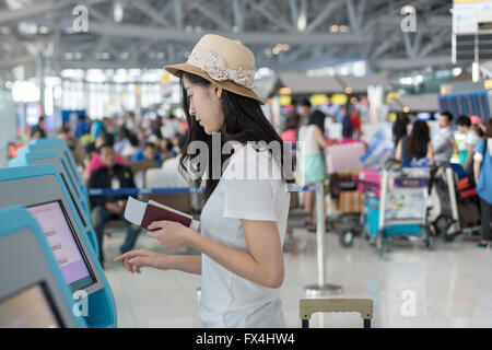 Young Asian woman en utilisant l'enregistrement automatique dans les kiosques à l'aéroport Banque D'Images