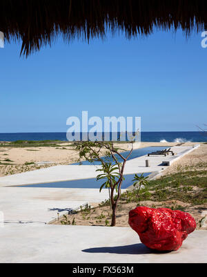 Vue depuis l'intérieur de la piscine et sur la mer vers Palapa avec Bosco Sodi sculpture en premier plan. Casa Wabi, Puerto Escondido, au Mexique. Archi Banque D'Images