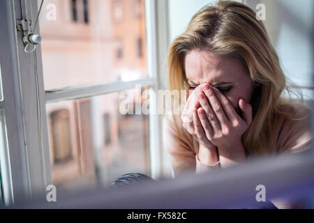 Woman sitting on windowsill, à la fenêtre de pleurer, Banque D'Images