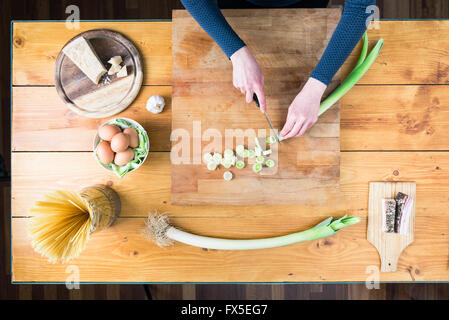 La préparation des pâtes carbonara's. Les mains des femmes préparer le poireau. Banque D'Images