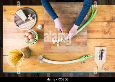 La préparation des pâtes carbonara's. Les mains des femmes préparer le poireau. Banque D'Images