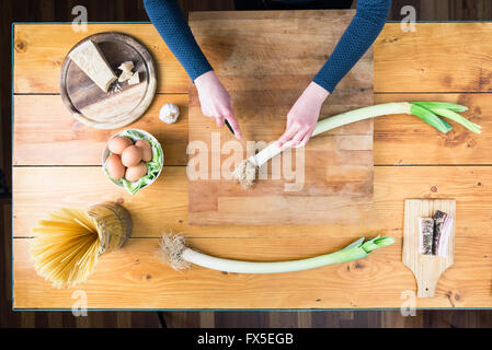 La préparation des pâtes carbonara's. Les mains des femmes préparer le poireau. Banque D'Images