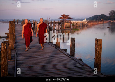 Deux moines à pied au lever du soleil à travers le pont de U Bein en bois près d'Amapura à Mandalay. Banque D'Images