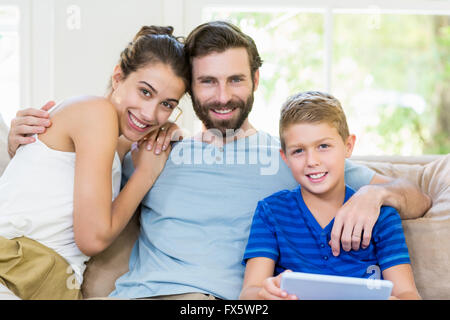 Portrait de parents et son fils assis sur le canapé avec bras autour de Banque D'Images