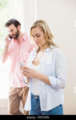 Femme textos Messagerie instantanée, tout en man talking on mobile phone Banque D'Images