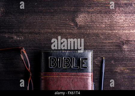 Bible, lunettes et un stylo posé sur une table en bois ancien Banque D'Images