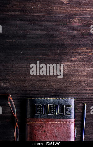 Bible, lunettes et un stylo posé sur une table en bois ancien Banque D'Images