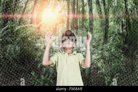 Mixed Race boy portant des lunettes de réalité virtuelle en forêt à distance Banque D'Images