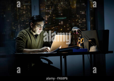 Mixed Race businessman travaillant tard in office Banque D'Images