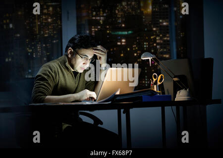 Mixed Race businessman travaillant tard in office Banque D'Images