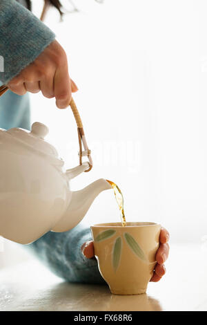 Hispanic woman pouring tasse de thé Banque D'Images