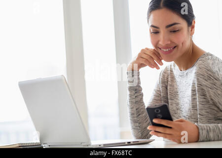 Hispanic woman using cell phone Banque D'Images