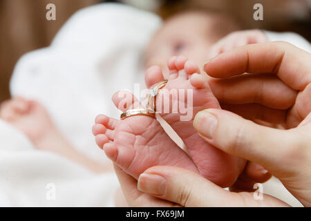 Les pieds de bébé avec les anneaux de mariage dans les mains de la mère Banque D'Images