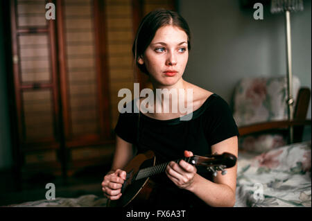 Caucasian woman playing ukulele dans la chambre Banque D'Images