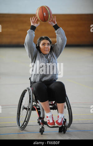 Une femme handicapée dans un fauteuil roulant de jeter un terrain de basket-ball. Banque D'Images