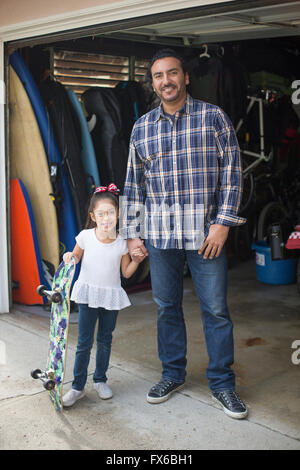 Hispanic father and daughter smiling in garage Banque D'Images