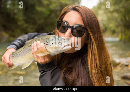 Caucasian woman kissing pêcher dans la rivière à distance Banque D'Images