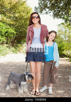 Caucasian mother and daughter walking dog on path Banque D'Images