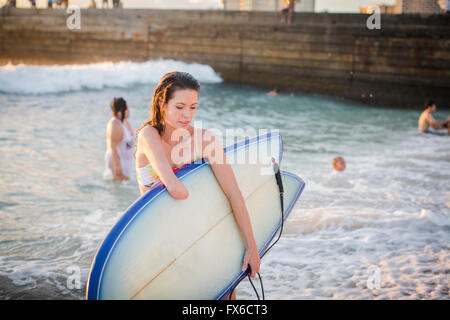 Mixed Race amputee transportant surfboard on beach Banque D'Images