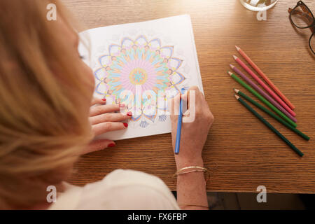 Vue aérienne de la femme dans l'élaboration des profils de coloriage avec des crayons de couleurs. Exercice anti-stress à la maison. Banque D'Images