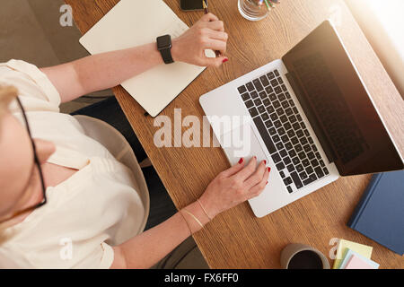 Vue de dessus d'une femme assise à son bureau et travaille sur ordinateur portable. Businesswoman working from home. Banque D'Images