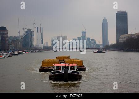 Bateau remorqueur tirant barge à conteneurs sur la Tamise sur une journée humide des pluies à Londres Banque D'Images