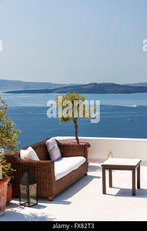 Table d'extérieur et canapés sur terrasse avec vue sur mer, le village d''Oia, Santorini, Cyclades, en Grèce. Banque D'Images