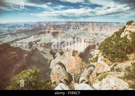 Vieux film rétro avec jambes stylisés usé des chaussures de randonnée sur le bord du Grand Canyon, profondeur de champ, vacances actives Banque D'Images