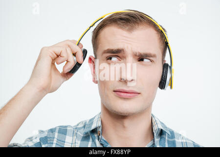 Beau jeune homme malheureux casque décollant sur fond blanc Banque D'Images