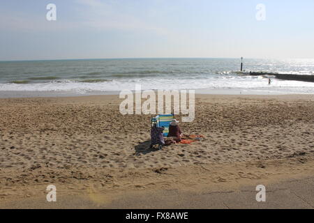 Une femme seule donne à voir une personne de la pagaie dans la mer à Southbourne Beach, Dorset, UK Banque D'Images