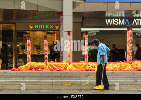 Homme balayant Orchard Road étapes après un festival chinois, à Singapour. Banque D'Images