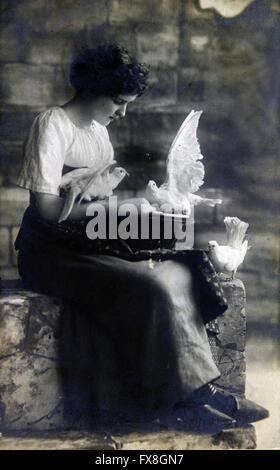 Allemagne - CIRCA 19100 : carte postale imprimée dans l'Allemagne montre femme assise sur les marches de pierre, l'alimentation colombes blanches Banque D'Images