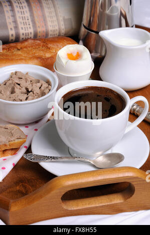 Le petit-déjeuner sur un plateau avec une tasse de café, des toasts avec le pâté de foie, oeuf dur et un journal Banque D'Images