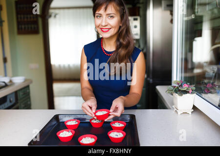 Jeune femme faisant un régime alimentaire des muffins dans la cuisine Banque D'Images