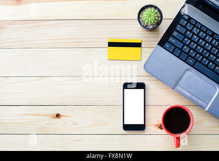 Travail de bureau avec ordinateur portable, tasse de café, carte de crédit et smartphone sur table en bois.vue d'en haut Banque D'Images