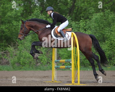 Teenage girl rider Aller au saut d'obstacle de bay horse Banque D'Images