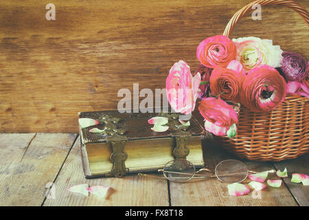 Vieux livre et verres à côté de beau champ de fleurs sur table en bois vintage filtrés. Banque D'Images