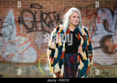 L'emplacement urbain modélisation photo : un jeune blond platine femme fille debout devant un mur couvert de graffitis Banque D'Images