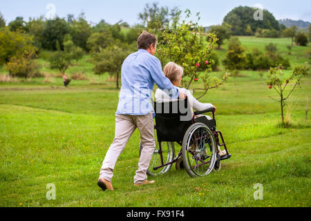 En poussant l'homme Senior woman in wheelchair, vert automne nature Banque D'Images