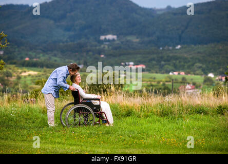 En poussant l'homme Senior woman in wheelchair, vert automne nature Banque D'Images