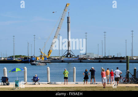 Port Canaveral, Floride, USA. 12 avril, 2016. Les gens regardent comme la première étape d'une fusée Falcon 9 SpaceX est hissé par une grue à Port Canaveral, Floride après son retour au port pendant la nuit sur un drone barge. La fusée a atterri avec succès sur la barge pour la première fois le 8 avril 2016 après avoir été lancée de Cap Canaveral avec un dragon spacecraft sur une mission de ravitaillement pour la Station spatiale internationale. SpaceX espère pouvoir réutiliser la fusée dans les mois à venir. Crédit : Paul Hennessy/Alamy Live News Banque D'Images