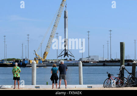 Port Canaveral, Floride, USA. 12 avril, 2016. Les gens regardent comme la première étape d'une fusée Falcon 9 SpaceX est hissé par une grue à Port Canaveral, Floride après son retour au port pendant la nuit sur un drone barge. La fusée a atterri avec succès sur la barge pour la première fois le 8 avril 2016 après avoir été lancée de Cap Canaveral avec un dragon spacecraft sur une mission de ravitaillement pour la Station spatiale internationale. SpaceX espère pouvoir réutiliser la fusée dans les mois à venir. Crédit : Paul Hennessy/Alamy Live News Banque D'Images