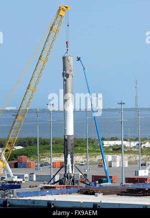 Port Canaveral, Floride, USA. 12 avril, 2016. Travailleurs d'un ascenseur, d'examiner la première étape d'une fusée SpaceX Falcon 9 à Port Canaveral, Floride après que le Rocket a été retourné au port pendant la nuit sur un drone barge. La fusée a atterri avec succès sur la barge pour la première fois le 8 avril 2016 après avoir été lancée de Cap Canaveral avec un dragon spacecraft sur une mission de ravitaillement pour la Station spatiale internationale. SpaceX espère pouvoir réutiliser la fusée dans les mois à venir. Véhicule de la NASA d'assemblage est vu dans la distance. Crédit : Paul Hennessy/Alamy Live News Banque D'Images