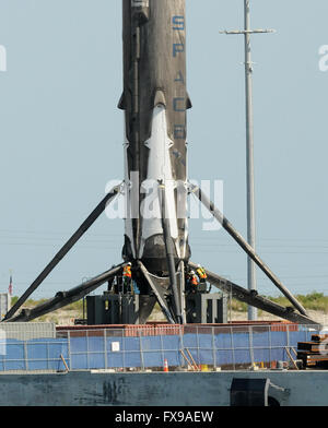 Port Canaveral, Floride, USA. 12 avril, 2016. Les travailleurs ont vu près de la quatre pattes d'un atterrissage SpaceX Falcon 9 rocket à Port Canaveral, Floride après que le Rocket a été retourné au port pendant la nuit sur un drone barge. La fusée a atterri avec succès sur la barge pour la première fois le 8 avril 2016 après avoir été lancée de Cap Canaveral avec un dragon spacecraft sur une mission de ravitaillement pour la Station spatiale internationale. SpaceX espère pouvoir réutiliser la fusée dans les mois à venir. Véhicule de la NASA d'assemblage est vu dans la distance. Crédit : Paul Hennessy/Alamy Live News Banque D'Images