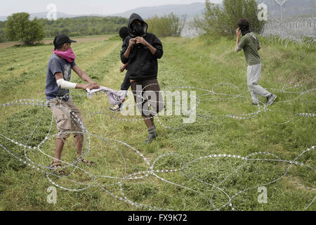 Idomeni, Grèce. 13 avr, 2016. Des centaines de migrants ont tenté de briser la barrière qui les sépare de la Macédoine, la police a répondu par des gaz lacrymogènes, des balles en caoutchouc et des bombes sonores après avoir réussi à forcer les migrants à travers la clôture. Des dizaines ont été blessées et touchés par le gaz lacrymogène. © Danilo Balducci/ZUMA/Alamy Fil Live News Banque D'Images