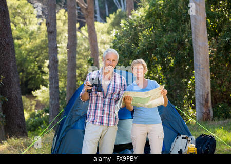 Young couple smiling and holding binoculars et carte Banque D'Images