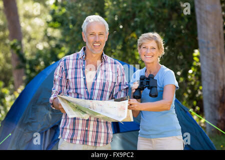 Young couple smiling and holding binoculars et carte Banque D'Images