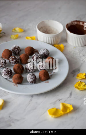 Vegan Chocolat amande boules date sur une plaque blanche Banque D'Images