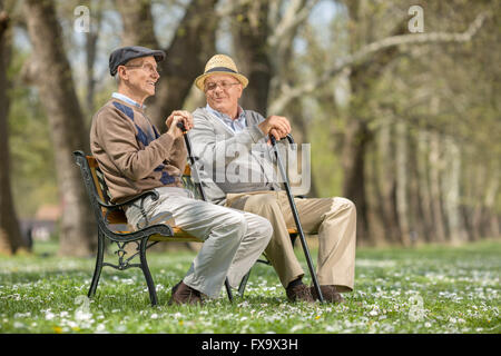 Deux vieux amis assis sur un banc en bois dans la région de Park et de parler les uns aux autres Banque D'Images