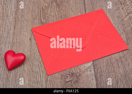 Enveloppe rouge et cœur rouge sur un fond de bois Banque D'Images